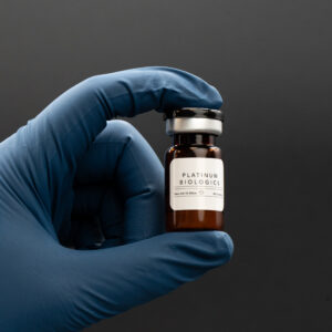 Hand holding a vial labeled "Platinum Biologics," showcasing a biological product relevant to health and wellness solutions.