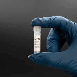 Hand holding a vial labeled "DPM" against a dark background, representing Platinumbiologics' biological product offerings.