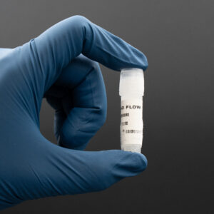 Gloved hand holding a vial labeled "Nano Flow," showcasing biologic product for health and wellness applications.
