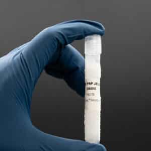 Hand holding a vial of Nano PRP Jelly, featuring a label with product information, against a dark background, relevant to Platinum Biologics' cosmetic and research offerings.