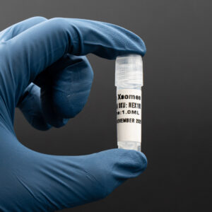 Hand holding a vial labeled "Xsomes" with dosage of 1.0 ml, showcasing Platinum Biologics' Nano Xsomes product for cosmetic and research applications.